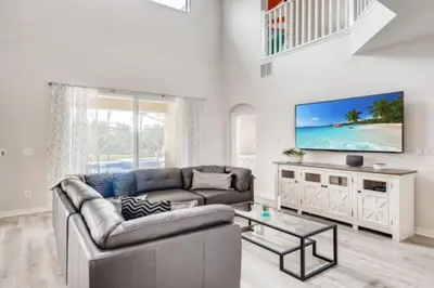 a living room with a couch and a tv at Lakefront 6BR Resort Pool Home Near Disney World in Kissimmee