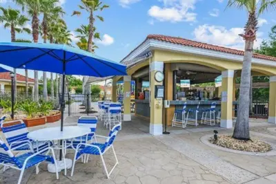 a patio with blue chairs and tables and umbrellas at Magical 7BR Resort Pool Home Near Disney World in Kissimmee