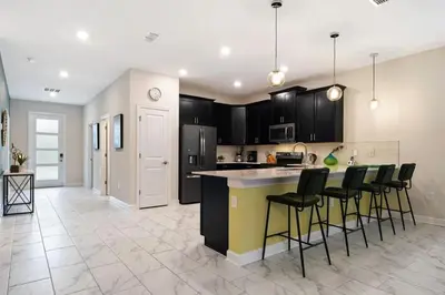 an open kitchen with black cabinets and bar stools at Vila incrível 9 quartos | Perto da Disney in Kissimmee