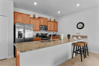 a kitchen with wooden cabinets and a stainless steel refrigerator at 4BR Townhome with Pool at Storey Lake in Kissimmee