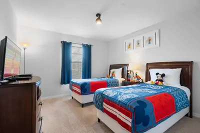 a bedroom with two beds and a desk and a television at 4BR Townhome with Pool at Storey Lake in Kissimmee