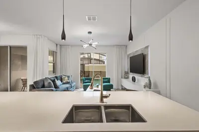 a kitchen with a sink and a living room at Stylish Family Retreat with Themed Bedrooms in Kissimmee