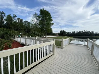 a wooden deck with a white fence and water at Relax and unwind in this Cozy Home Away from Home in Kissimmee