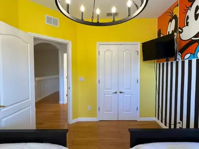 a bedroom with yellow walls and a chandelier at 2335 Amazing 5BD Family Townhome Close to Disney in Kissimmee