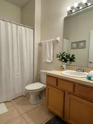 a bathroom with a toilet and a sink and a mirror at 2335 Amazing 5BD Family Townhome Close to Disney in Kissimmee