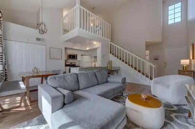 a living room with a gray couch and a kitchen at Charming and Cozy Townhome Near Disney in Kissimmee