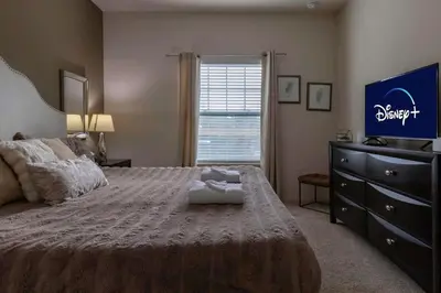 a bedroom with a bed with a dresser and a television at 4BR Family Townhouse Steps to Disney in Kissimmee