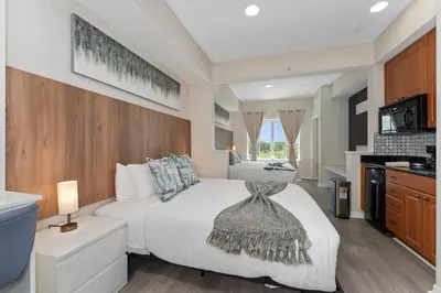 a bedroom with a white bed and a kitchen at King Queen Spacious Studio Near Universal in Orlando