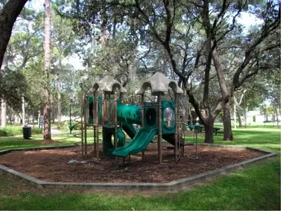 a green playground in a park with trees at Sunny Oaks Poolside, pool spa games,4m to Disney in Orlando