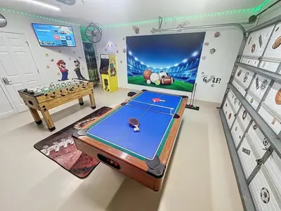 a room with a ping pong table and a large screen at Sunny Oaks Poolside, pool spa games,4m to Disney in Orlando