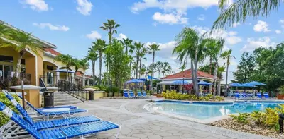 a resort pool with blue lounge chairs and palm trees at Holiday Haven at Terra Verde Resort in Kissimmee