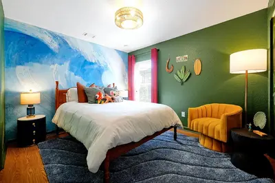 a bedroom with a large bed with a painting on the wall at Whimsical Mouse Manor in Orlando