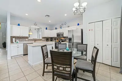 a kitchen with white cabinets and a table and chairs at 7 Bed Family Villa for All in Kissimmee