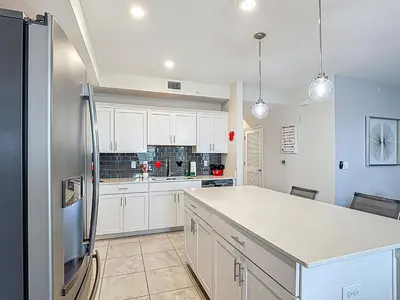 a kitchen with white cabinets and a refrigerator at Storey Lake Beautiful 2-BR Condo, Resort Amenities in Kissimmee
