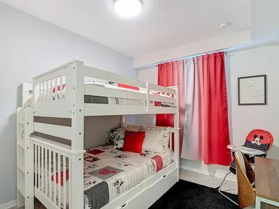 a white bunk bed in a bedroom with a red curtain at Storey Lake Beautiful 2-BR Condo, Resort Amenities in Kissimmee