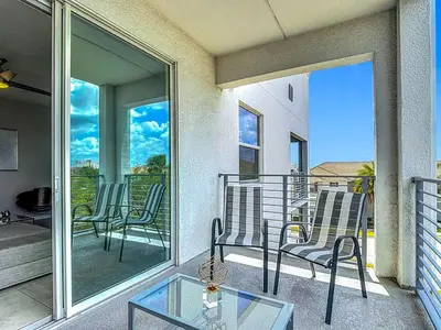 a balcony with chairs and a glass table at Storey Lake Beautiful 2-BR Condo, Resort Amenities in Kissimmee