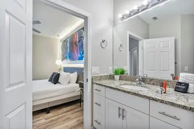 a bathroom with a sink and a bedroom with a bed at Thematic 4 bdr near Disney-22101 in Kissimmee