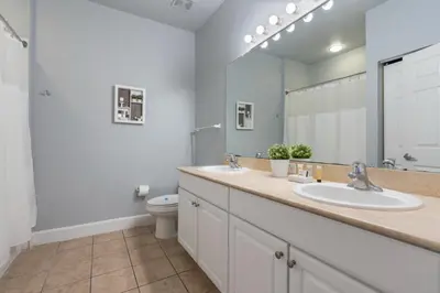 a bathroom with two sinks and a toilet and a mirror at Your Disney Vacation Home 7102 in Kissimmee