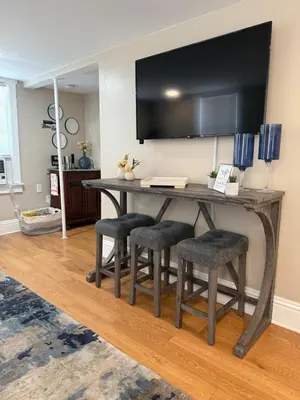 a wooden table with stools and a television on a wall at Cute and Cozy Apt Near Historic Downtown Sanford in Sanford
