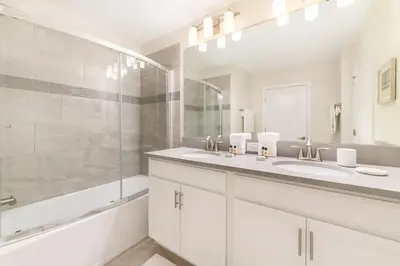 a white bathroom with two sinks and a shower at 4827#2 Casa com Quartos Temáticos e Piscina Privativa in Kissimmee