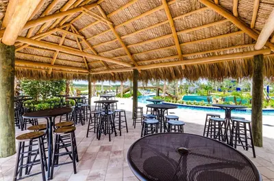 a restaurant with tables and chairs under a straw roof at Bright Cheery Vacation Villa-1638St in Kissimmee
