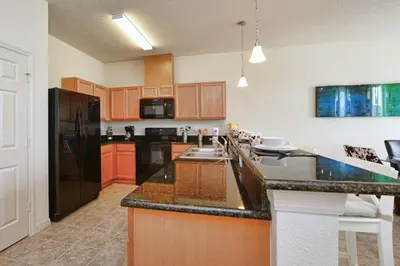 a kitchen with a black refrigerator and wooden cabinets at Charming Waterfront Townhome - 1954Cy in Kissimmee