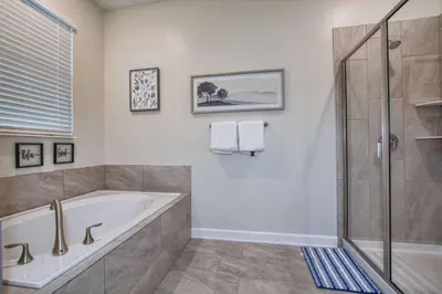a bathroom with a tub and a shower at Storey Lake 8 Bed Lake Front Pool Spa - 1684Str in Kissimmee