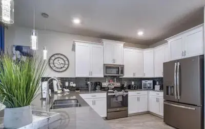 a kitchen with white cabinets and a clock on the wall at Beautiful Brand New Waterfront Retreat!1689St in Kissimmee