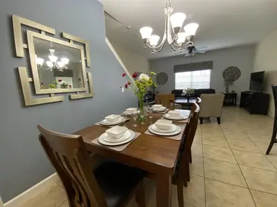 a dining room and living room with a wooden table at Paradise Palms- 5 Bed Townhome Wsplashpool-3020Pp in Kissimmee