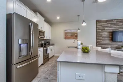 a kitchen with a stainless steel refrigerator and white cabinets at Modern Decor, Waterview With Splashpool, Bbq 1636Str in Kissimmee