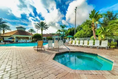 a swimming pool with white chairs and a resort at Beautiful Resort 3 Bedrooms Condo Near Disney in Kissimmee
