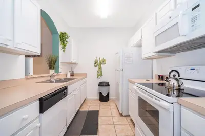 a kitchen with white cabinets and a sink at Beautiful Resort 3 Bedrooms Condo Near Disney in Kissimmee