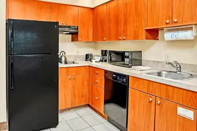 a kitchen with a black refrigerator and wooden cabinets at Chic Apartment near Disney w Pool Hot Tub Arcade in Orlando