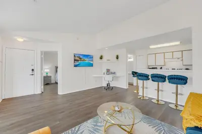 a living room with blue chairs and a kitchen at Elegant and cozy 2 BD condo near Disney in Kissimmee