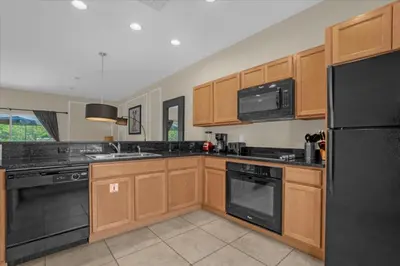 a kitchen with wooden cabinets and a black refrigerator at 3 Bedrooms 2 Bathrooms Encantada 3070 Wo in Kissimmee
