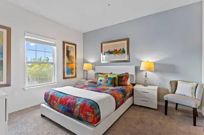 a white bedroom with a bed and a chair at New 4BDR House near Disney 8979 in Kissimmee