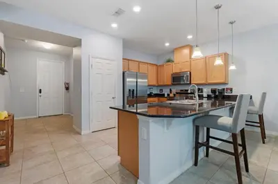 a kitchen with a counter and a kitchen island with chairs at Family House near Disney - 5109 in Kissimmee
