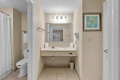 a bathroom with a sink and a toilet and a mirror at Hotel Room Next to Universal At Stay Sky Suites in Orlando