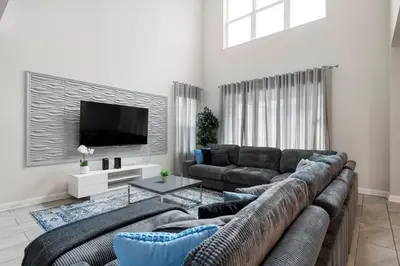 a living room with a large couch and a tv at Family 5BR Retreat w Pool Near Disney in Kissimmee