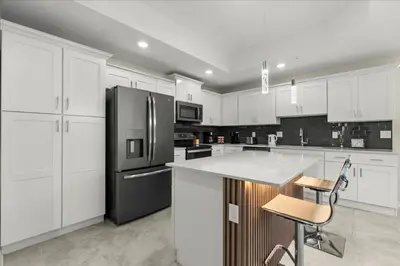 a kitchen with white cabinets and a black refrigerator at 3 Bedrooms 2 Bathrooms Storey Lake 3180-308 in Kissimmee