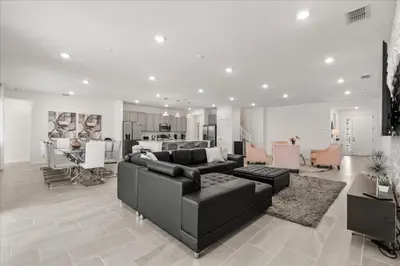 a living room with a black couch and a kitchen at 15 Bedrooms155 Bathroomsveranda Palms 2477Rd in Kissimmee