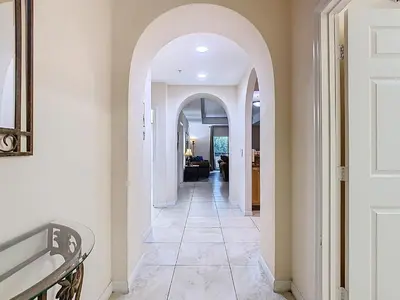 an arched hallway with white walls and tile floors at 3BR Cozy Apartment at Caribe Cove Resort Near Disney! in Kissimmee
