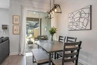 a dining room and living room with a table and chairs at Casa c/ Piscina Privativa a 10min da Disney in Kissimmee