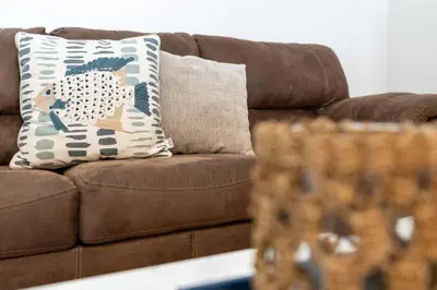 a brown couch with a blue and white pillow on it at Cozy 3BDR House near Disney - AL in Orlando