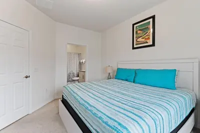 a white bedroom with a bed with blue sheets at Amazing 4BDR few miles from Disney in Kissimmee