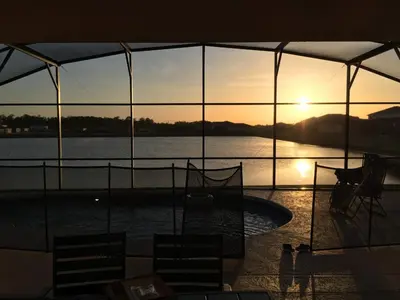 a view of a pool with the sun setting over the water at 4BDR with pool near Disney 1014 in Kissimmee