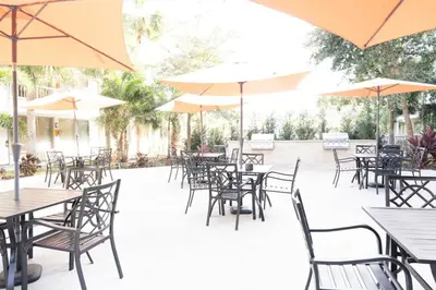 an outdoor patio with tables and chairs and umbrellas at Modern New APT in perfect Location only 10min to Disney in Kissimmee