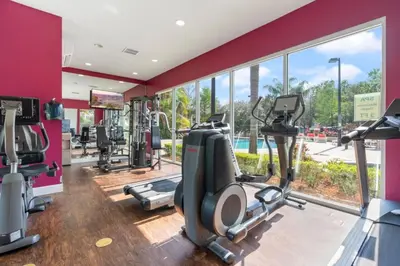 a gym with treadmills elliptical machines and a large window at Amazing 3Bdr House near Disney 16106 in Kissimmee