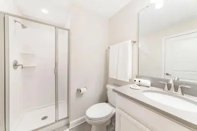 a white bathroom with a toilet and a sink at Casa 5 Quartos c/ Piscina Privativa no Storey Lake in Kissimmee