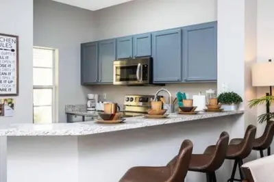 a kitchen with blue cabinets and a counter with chairs at Emerald Island Resort townhouse 3 Bedrooms in Kissimmee
